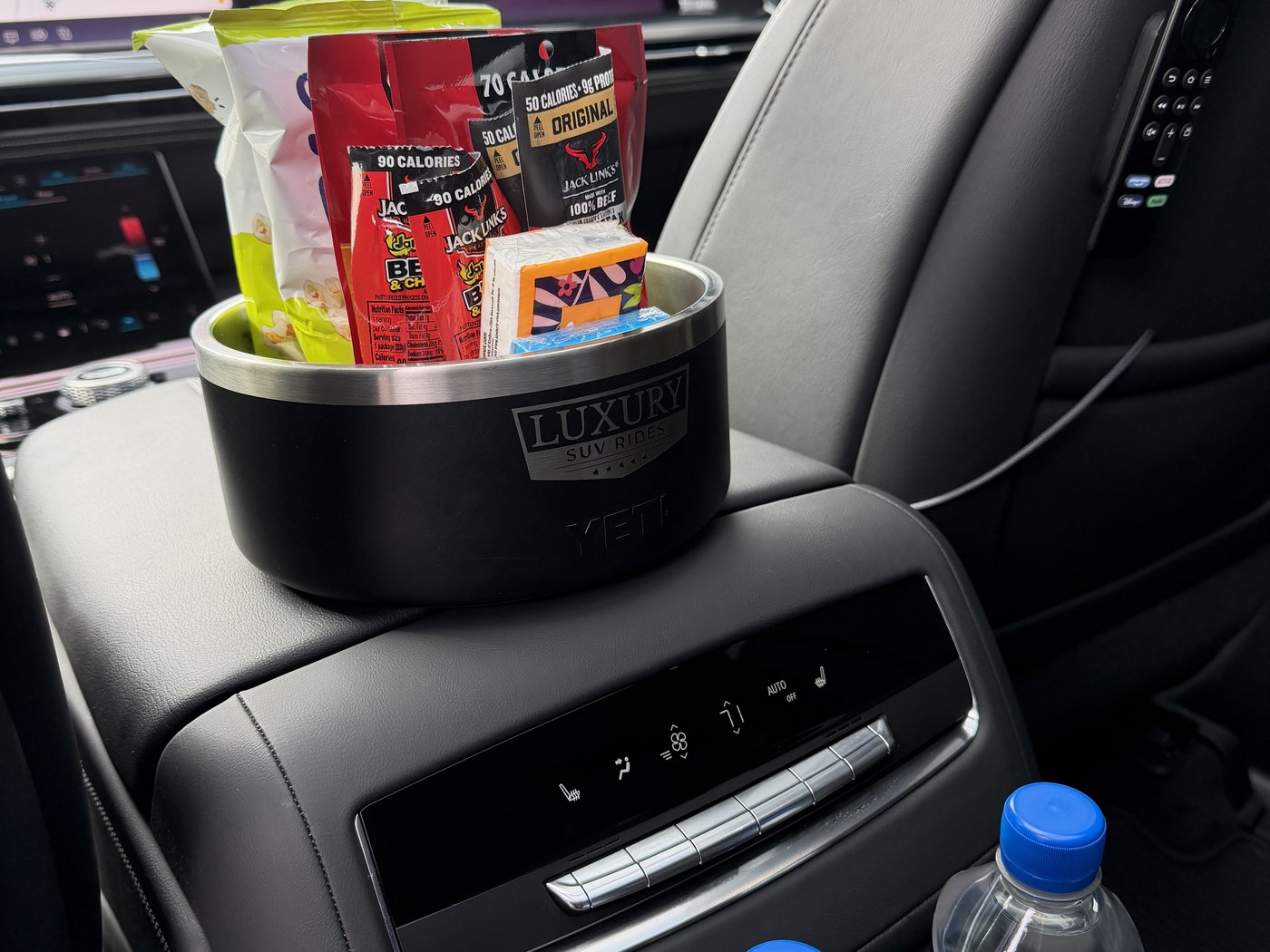 The rear console of a Cadillac Escalade ESV with a chilled bottled water and refreshments in a branded ice bucket