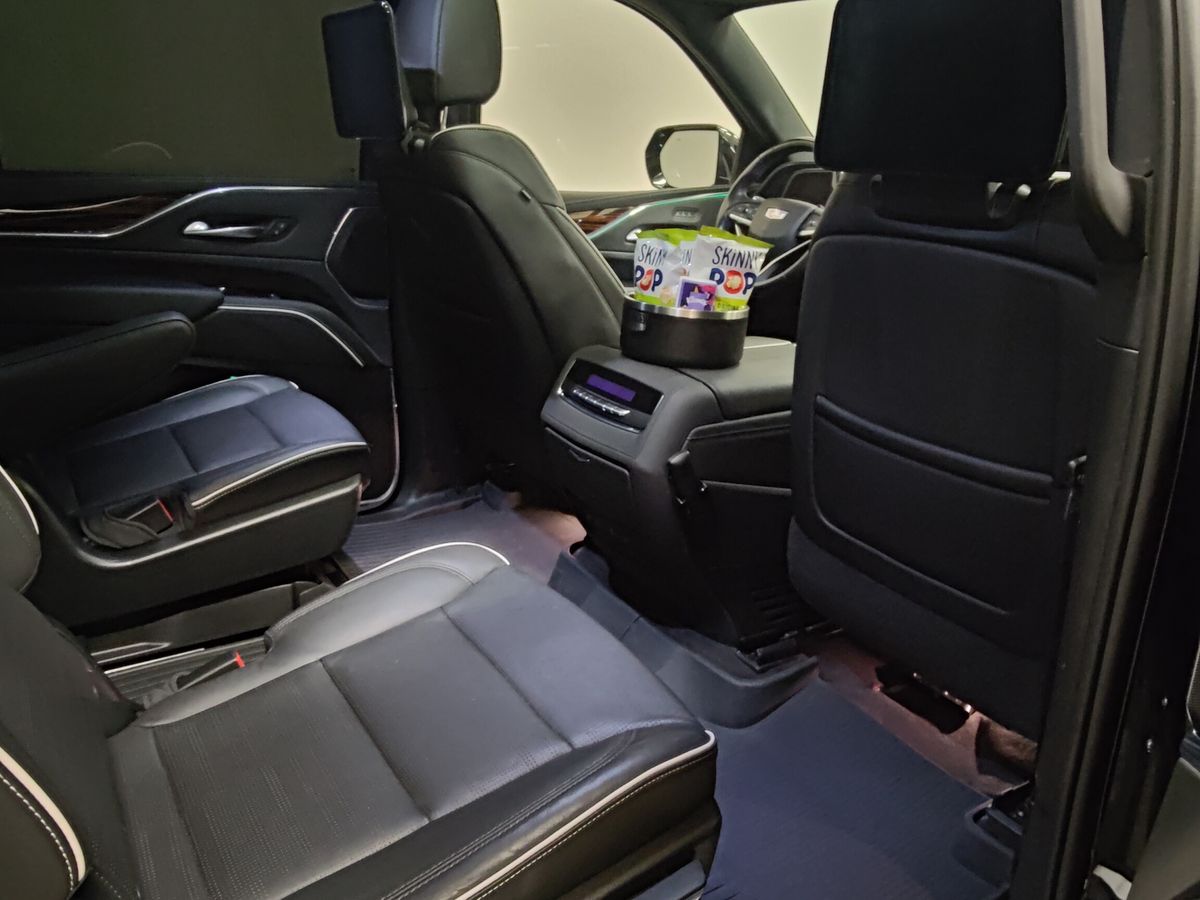 Interior of a Cadillac Escalade ESV looking back through the open rear door, panoramic sunroof above the second row