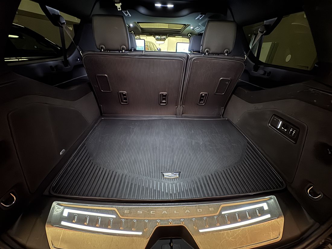 The rear cargo area of a Cadillac Escalade ESV, empty, lit, with the load floor clear