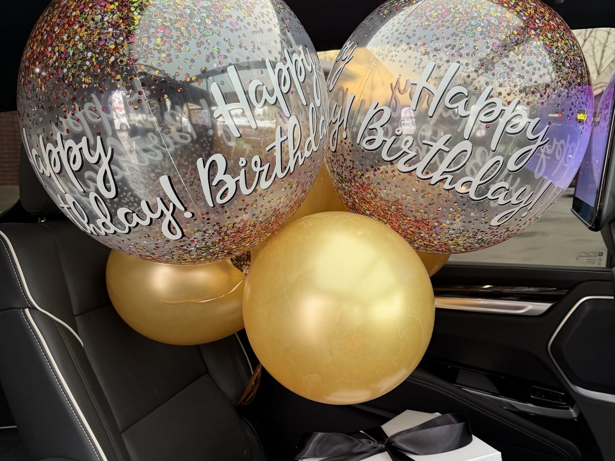 Balloons and a gift bag waiting in the second row of a Cadillac Escalade ESV before a birthday pick-up