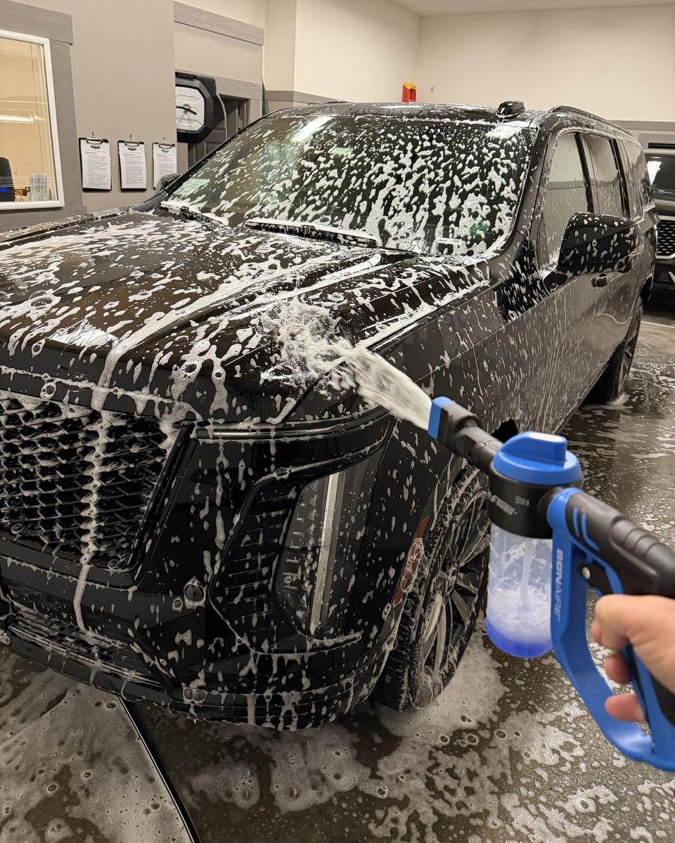 A Cadillac Escalade ESV covered in foam being washed by hand at the Luxury SUV Rides garage