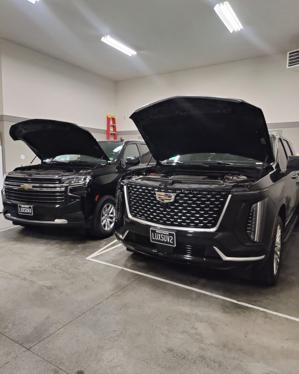 Two SUVs with their hoods raised for a pre-trip inspection in the garage