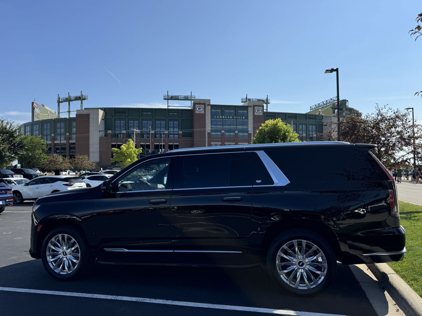 Black Cadillac Escalade ESV parked in front of the Lambeau Field atrium on a clear game day