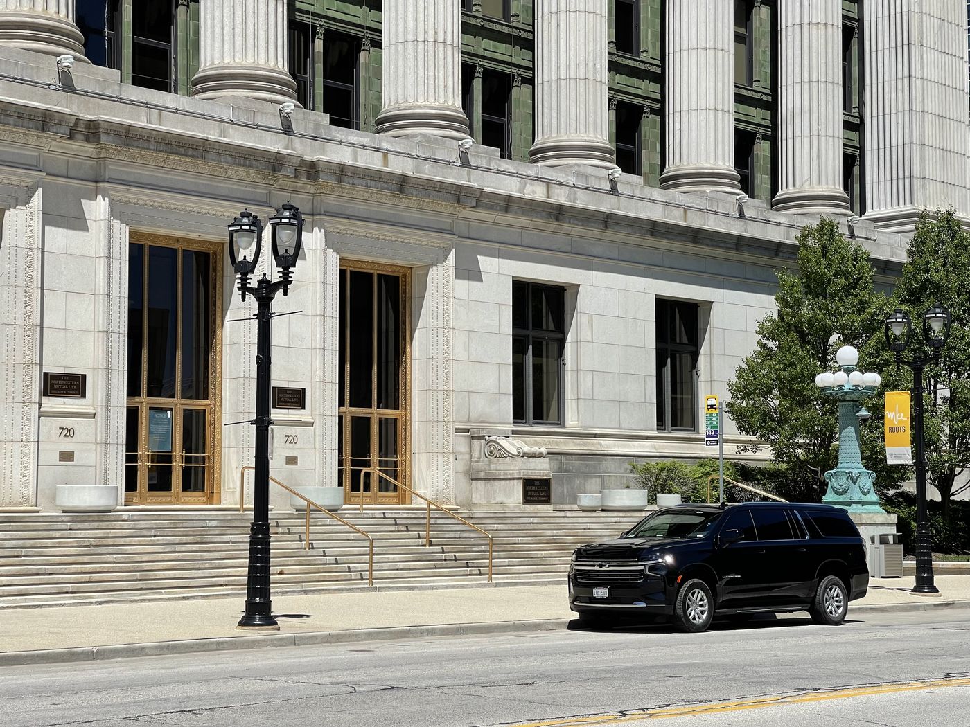 Black Chevrolet Suburban waiting at the curb outside a downtown Milwaukee office building