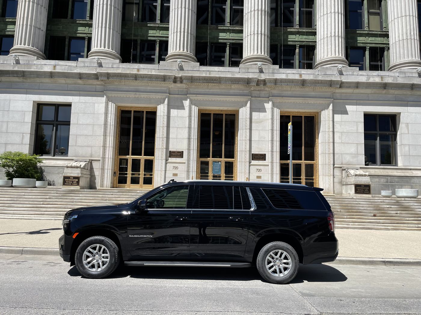 Black Chevrolet Suburban outside a downtown Milwaukee office building, a River Hills corporate destination