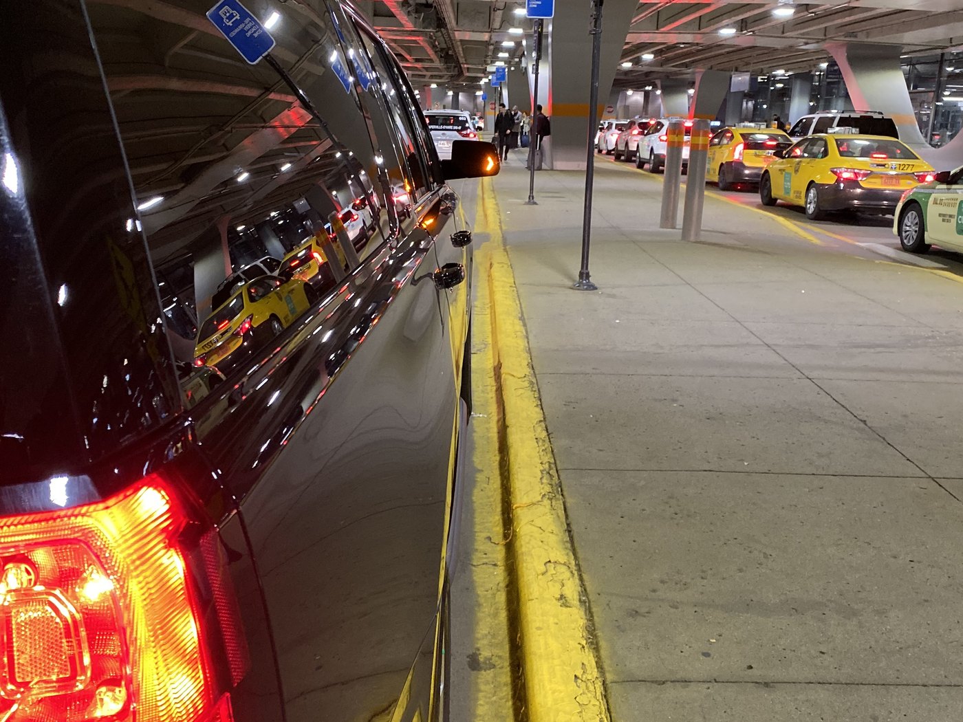 Black SUV waiting at the arrivals curb at O'Hare International, the taxi line beyond