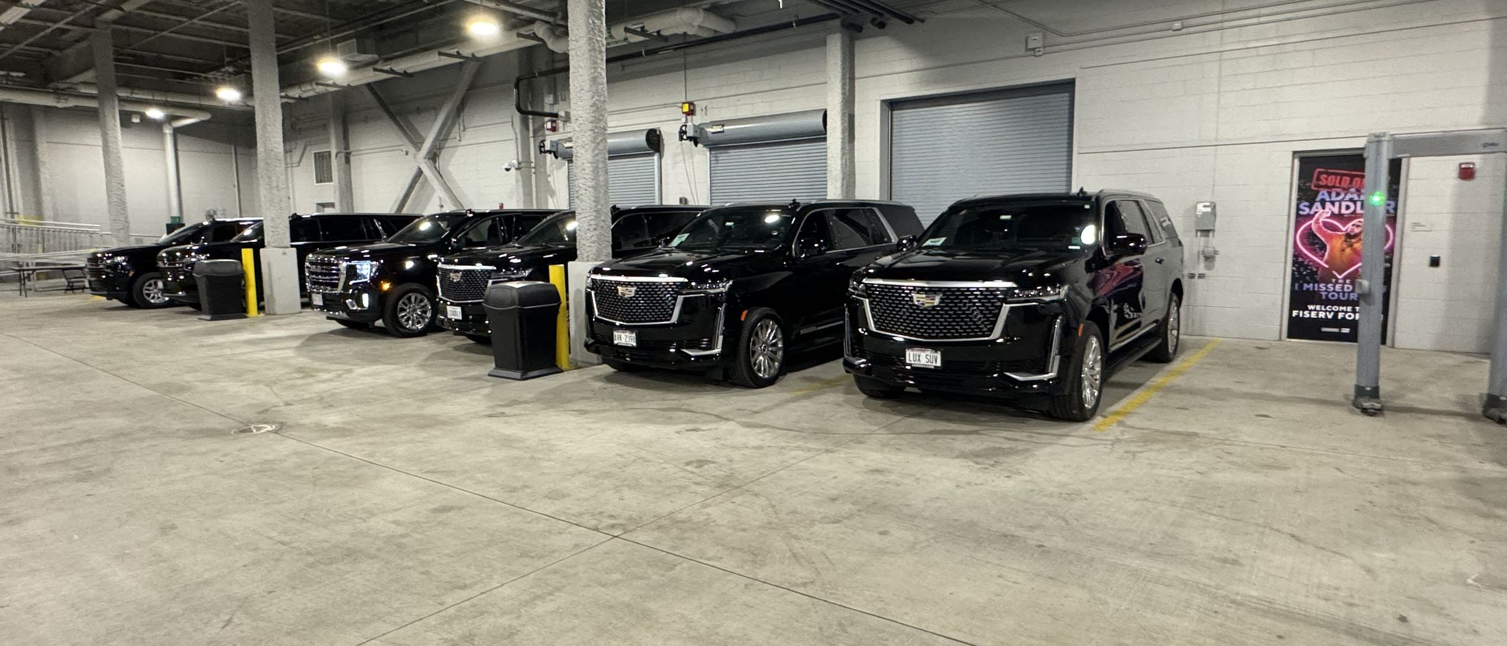 Black Cadillac Escalades staged in a parking structure before a multi-vehicle corporate booking, the kind a Racine headquarters visit calls for